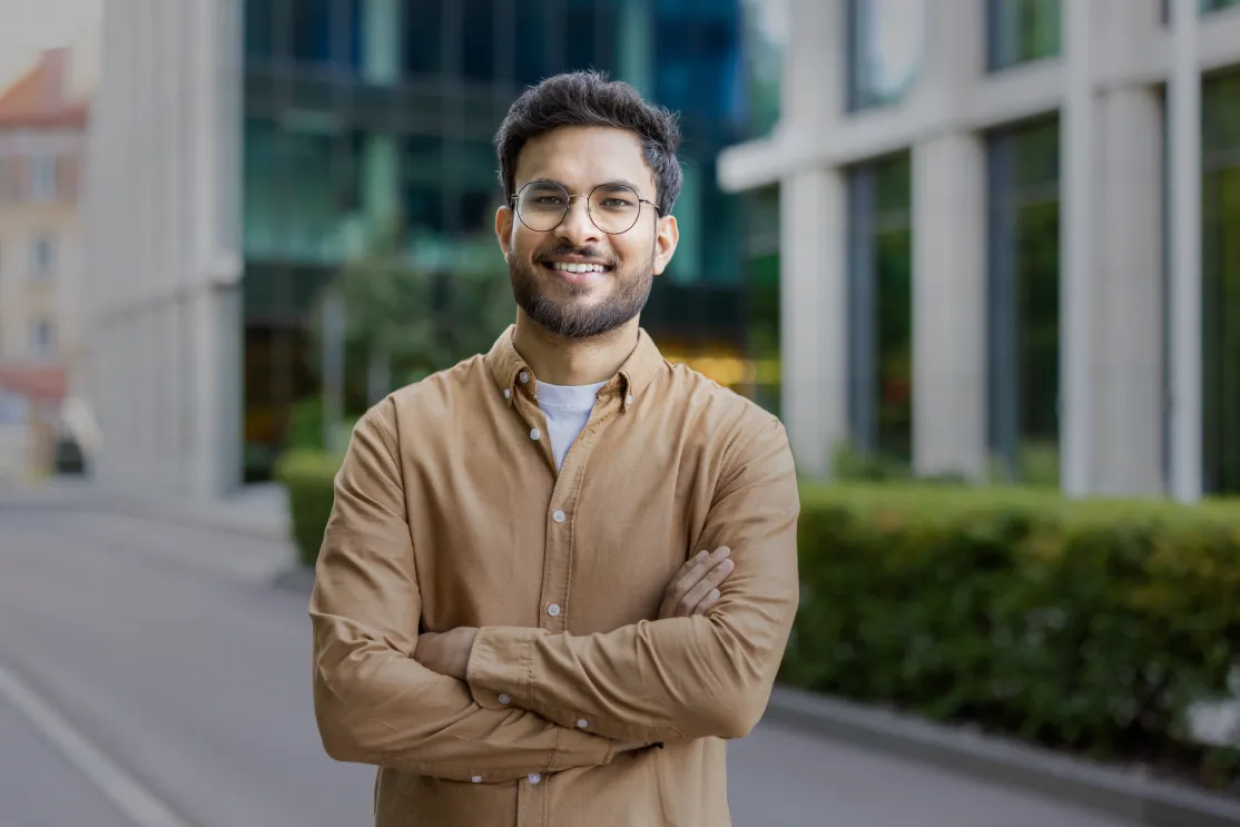 Man with glasses smiling with arms crossed